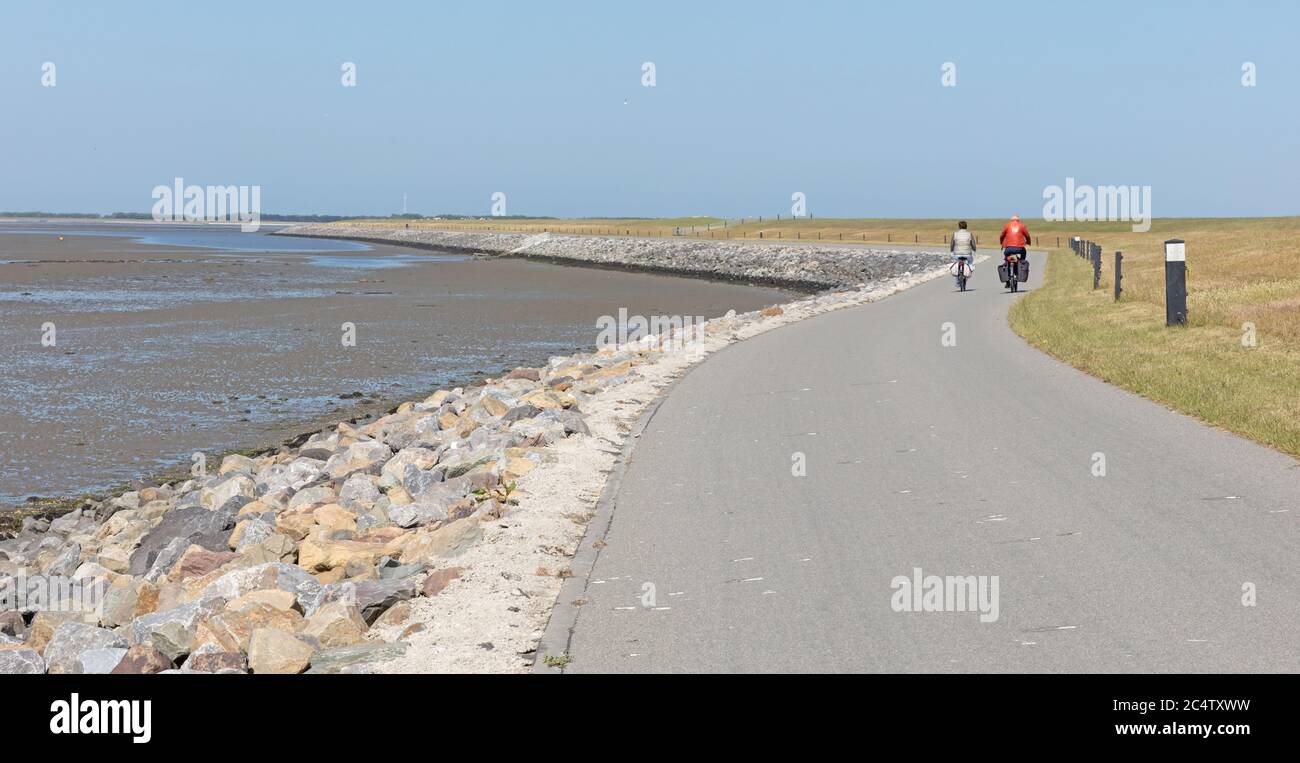 Cyclists cycling on a dyke, dutch Isle of Ameland Stock Photo