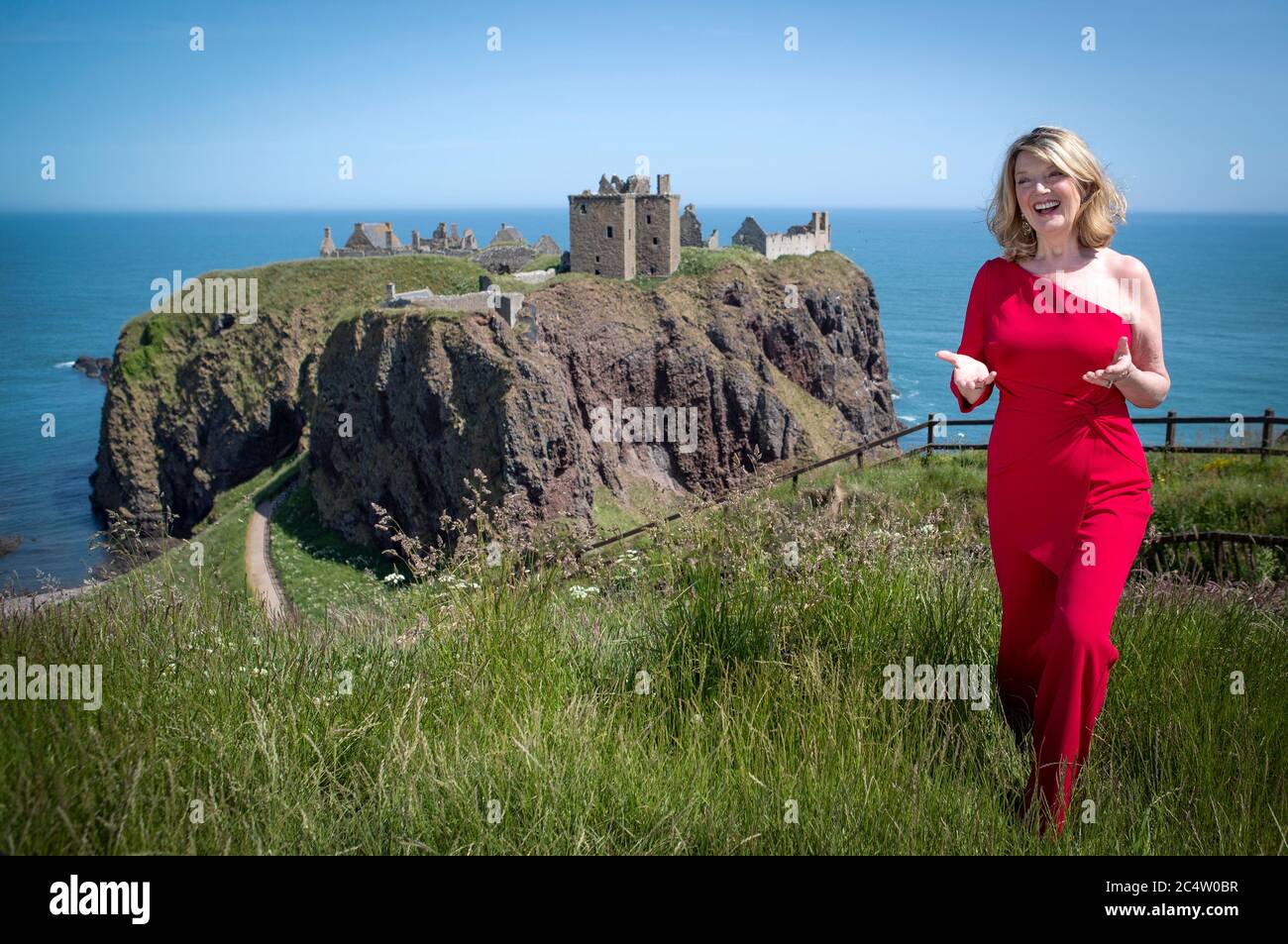 Scottish singer, song-writer and broadcaster Fiona Kennedy sings 'Stronger for the Storm', a new international song of peace, on the clifftop overlooking Dunnottar Castle on the Aberdeenshire coast, at the launch of iSing4Peace on the anniversary of the signing of the Treaty of Versailles which brought an official end to the First World War and restored peace to the world. Stock Photo