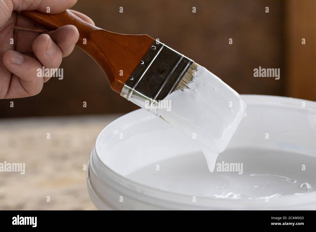 man holds brush in his hand ready to paint with white acrylic paint