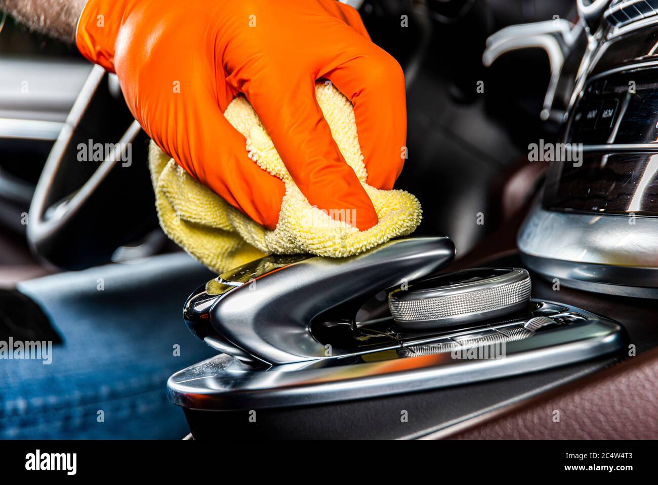 A man cleaning car interior panels and dashboard with yellow microfiber cloth. Car detailing or valeting concept. Selective focus. Car detailing. Clea Stock Photo