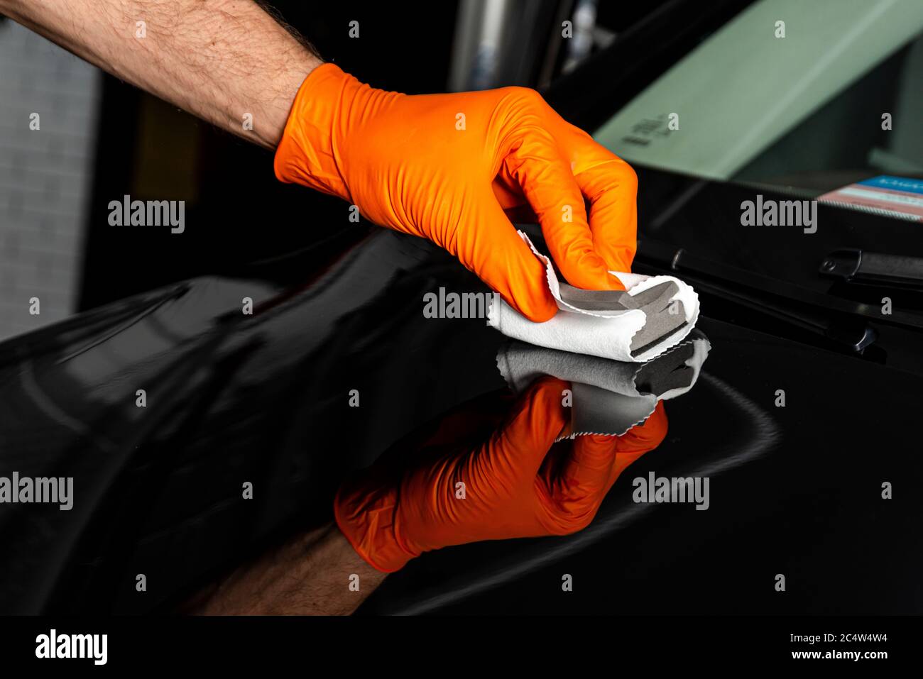 Car polish wax worker hands polishing car. Buffing and polishing vehicle with ceramic. Car detailing. Man holds a polisher in the hand and polishes th Stock Photo