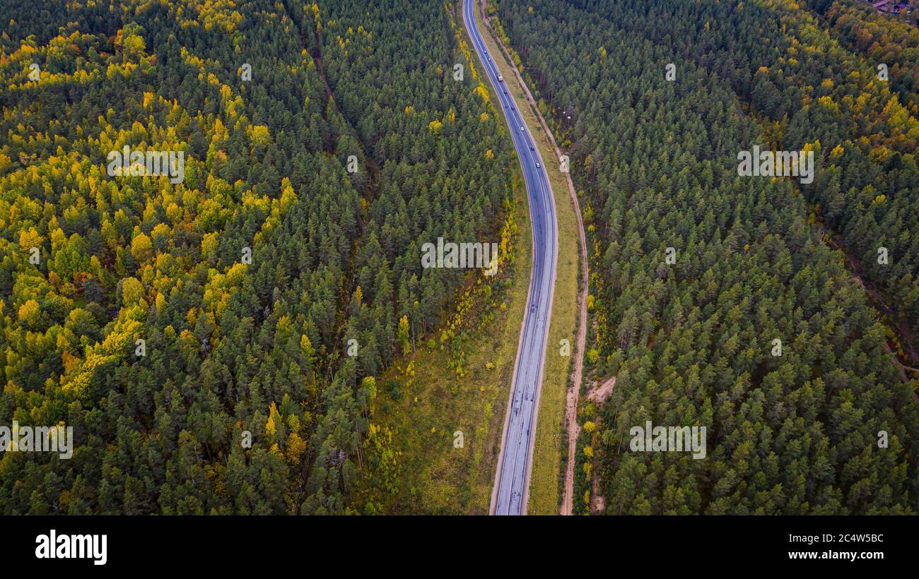 Aerial view of a car on the road. Autumn landscape countryside. Aerial photography of autumn forest with a car on the road. Captured from above with a Stock Photo