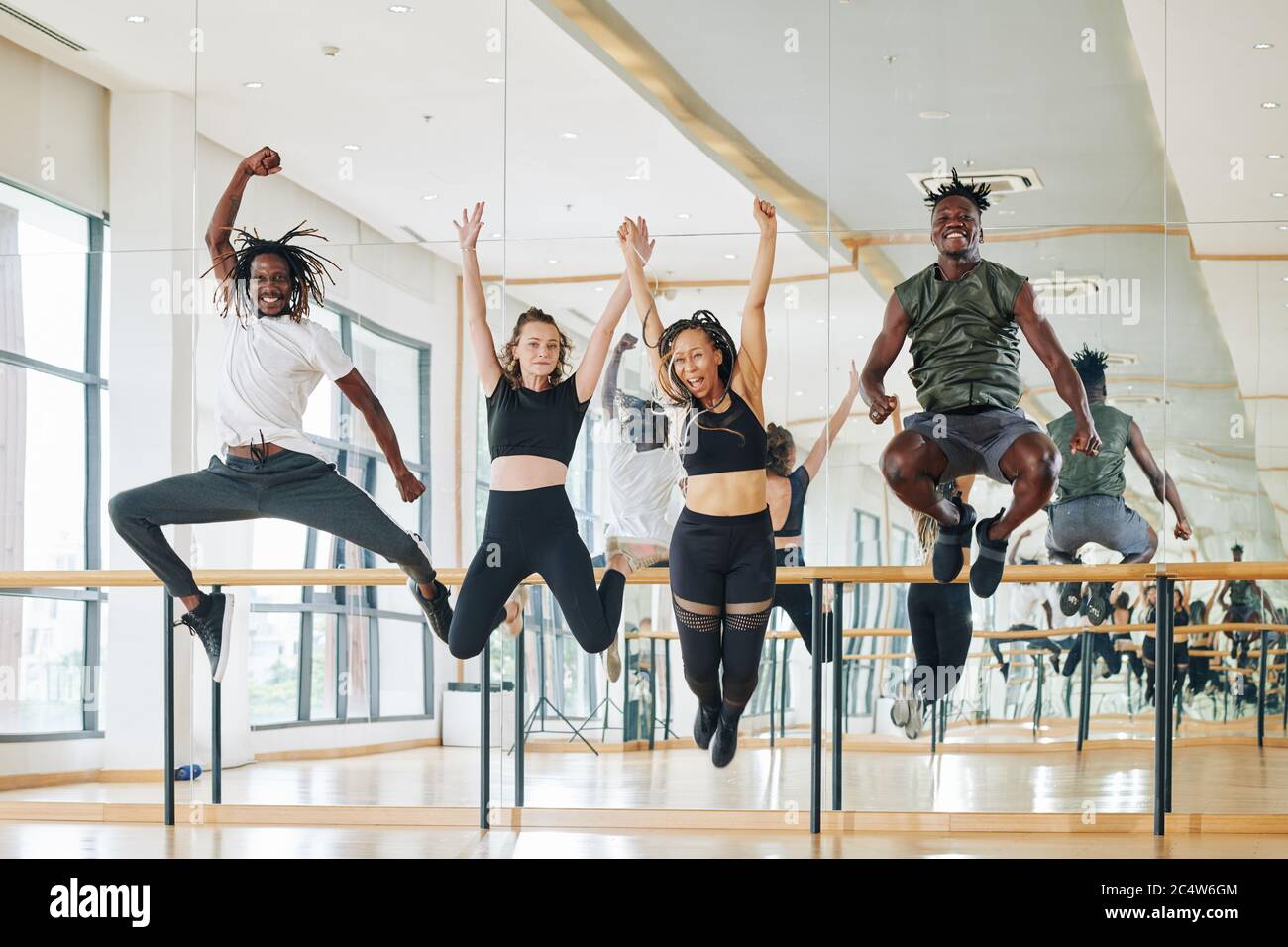 Multi-ethnic group of happy dancers jumping from excitement after productive training Stock Photo