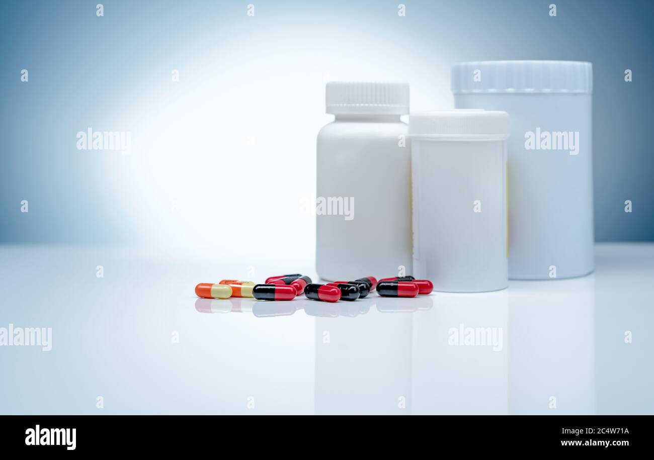 Antibiotic capsule pills and blank label plastic drug bottle on gradient background. Pharmaceutical industry. Antibiotic drug resistance. Antibiotics. Stock Photo