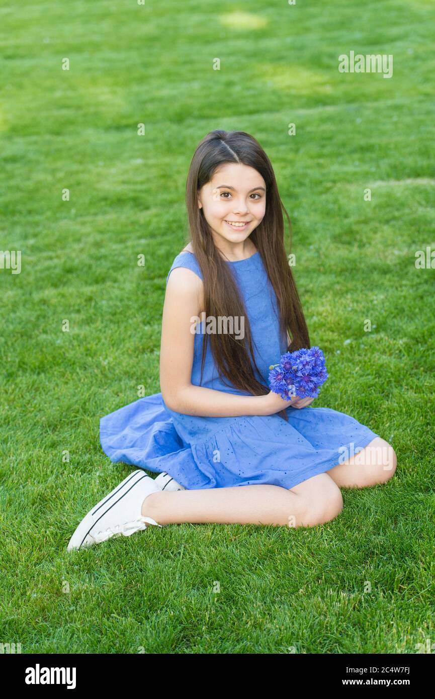 Relax, unwind and indulge. Happy child sit on green grass. Beauty look of  child girl. Little child with long hair in casual style. Summer fashion  trends. Child care and childhood. Childrens day