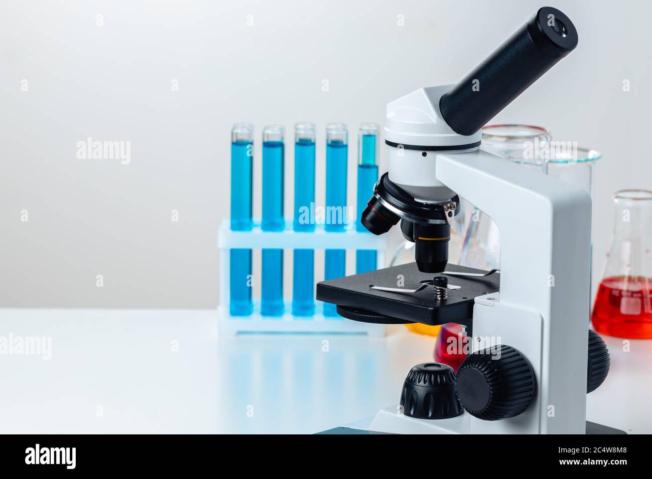 Close up of laboratory microscope with set of test tubes with blue ...