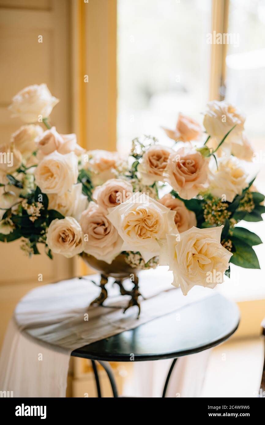 bouquet of tender cream roses in copper vase on the table in the room ...