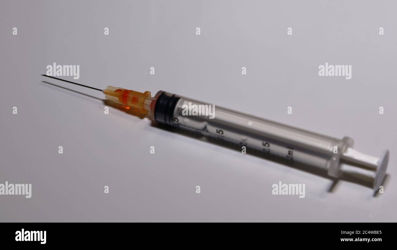 A one-time-use syringe and hypodermic needle are assembled, waiting to be filled. Stock Photo