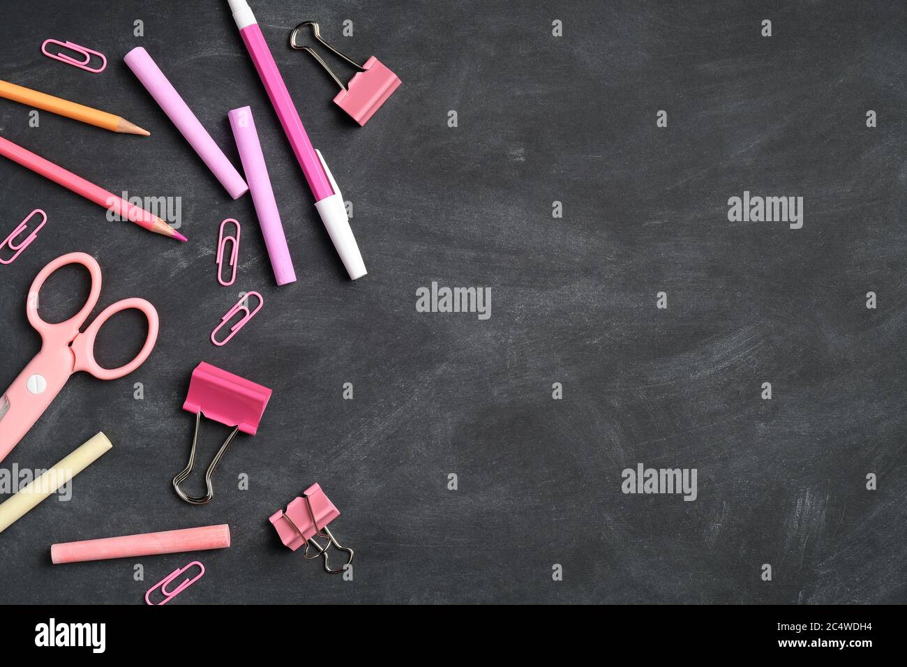 Pink school supplies on blackboard background. Flat lay, top view