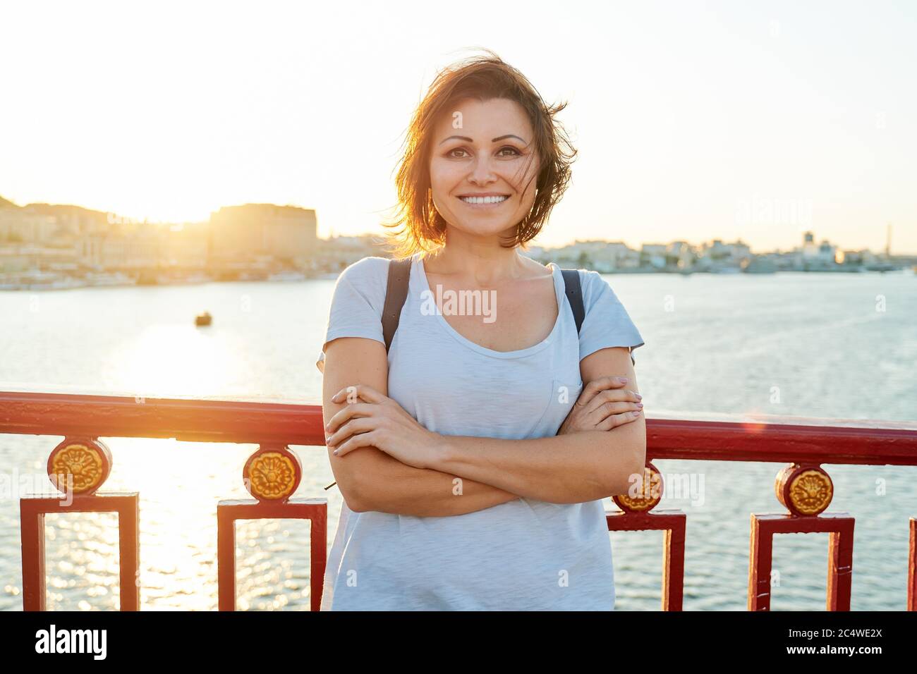 Lifestyle outdoor portrait of mature smiling woman with folded arms Stock Photo