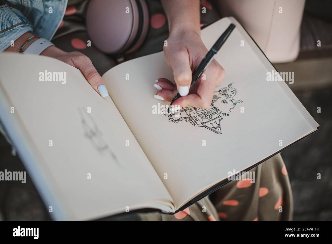 Sketchbook with a drawing of a house close-up. Girl draws with her left hand. Stock Photo