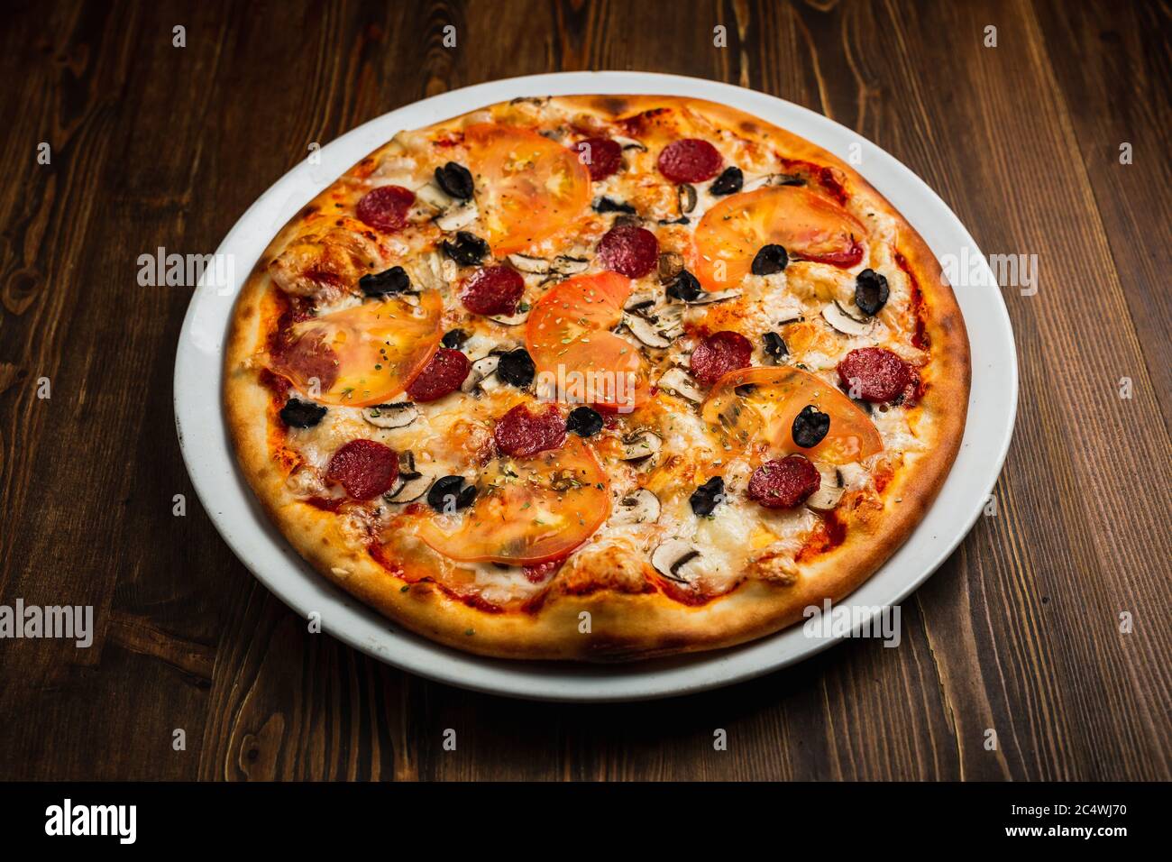 Pepperoni, mushroom, black olives, tomato and cheese pizza, wooden