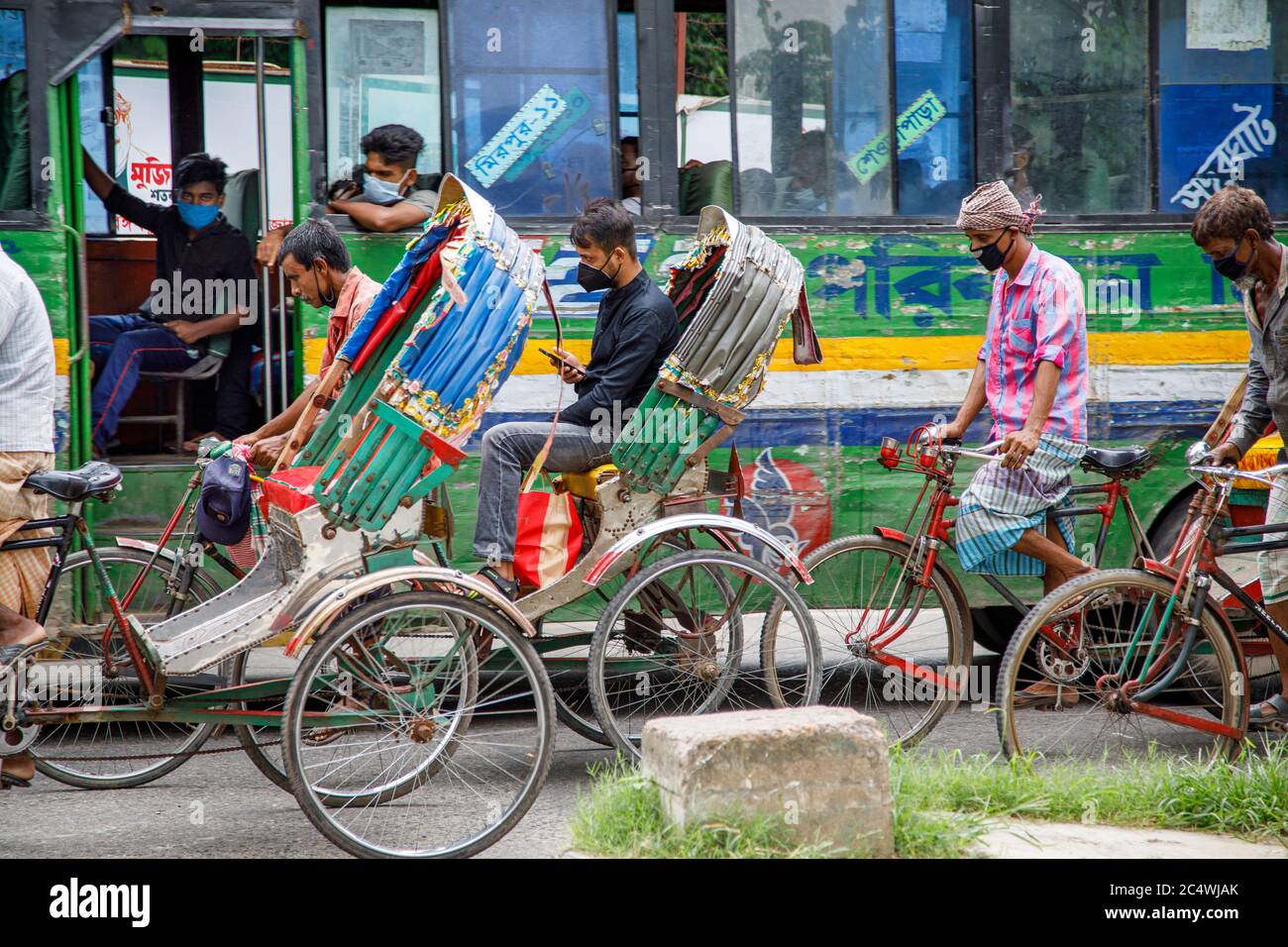Ricksha-walas, or  rickshaw drivers with their passengers on the streets of Dhaka. Residents in the Bangladesh Capital Dhaka are adjusting to the threat from the COVID 19 corona virus. Stock Photo