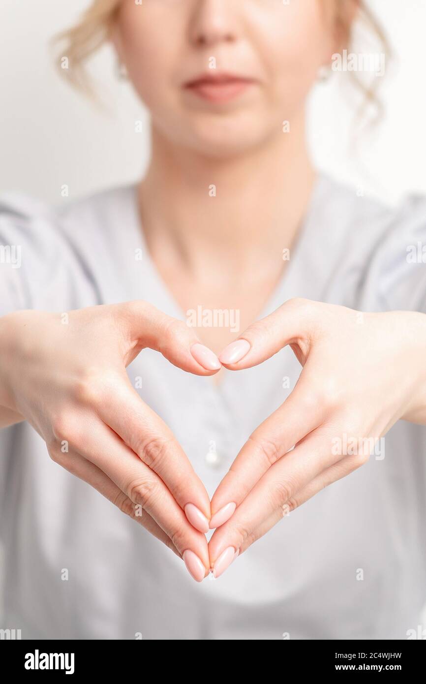 Close up of young caucasian woman making heart shape by hands. Romantic concept. Stock Photo