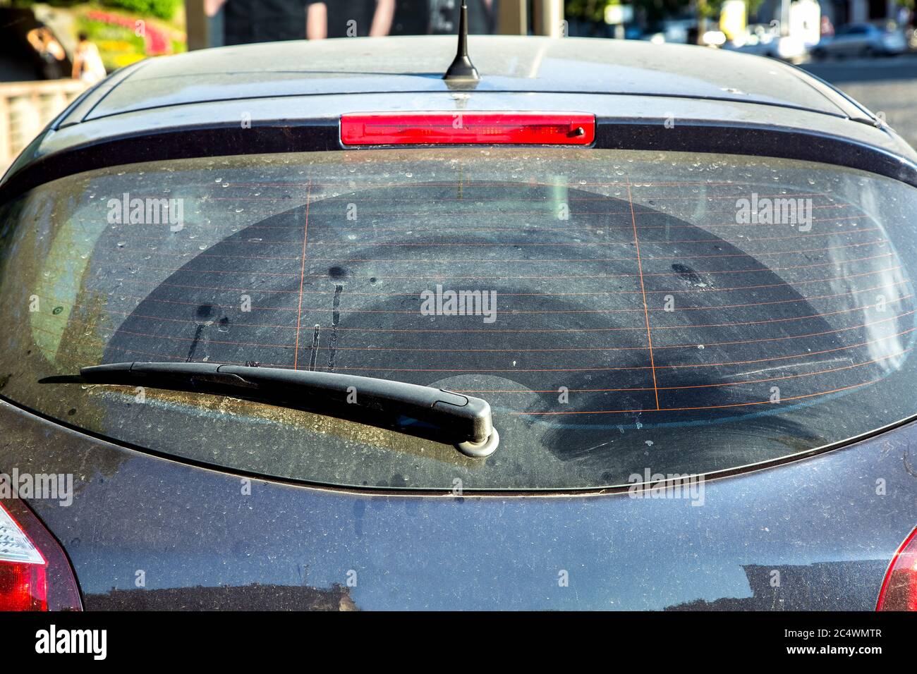 Dirty car rear window, car wagon covered with dust outside in sunny