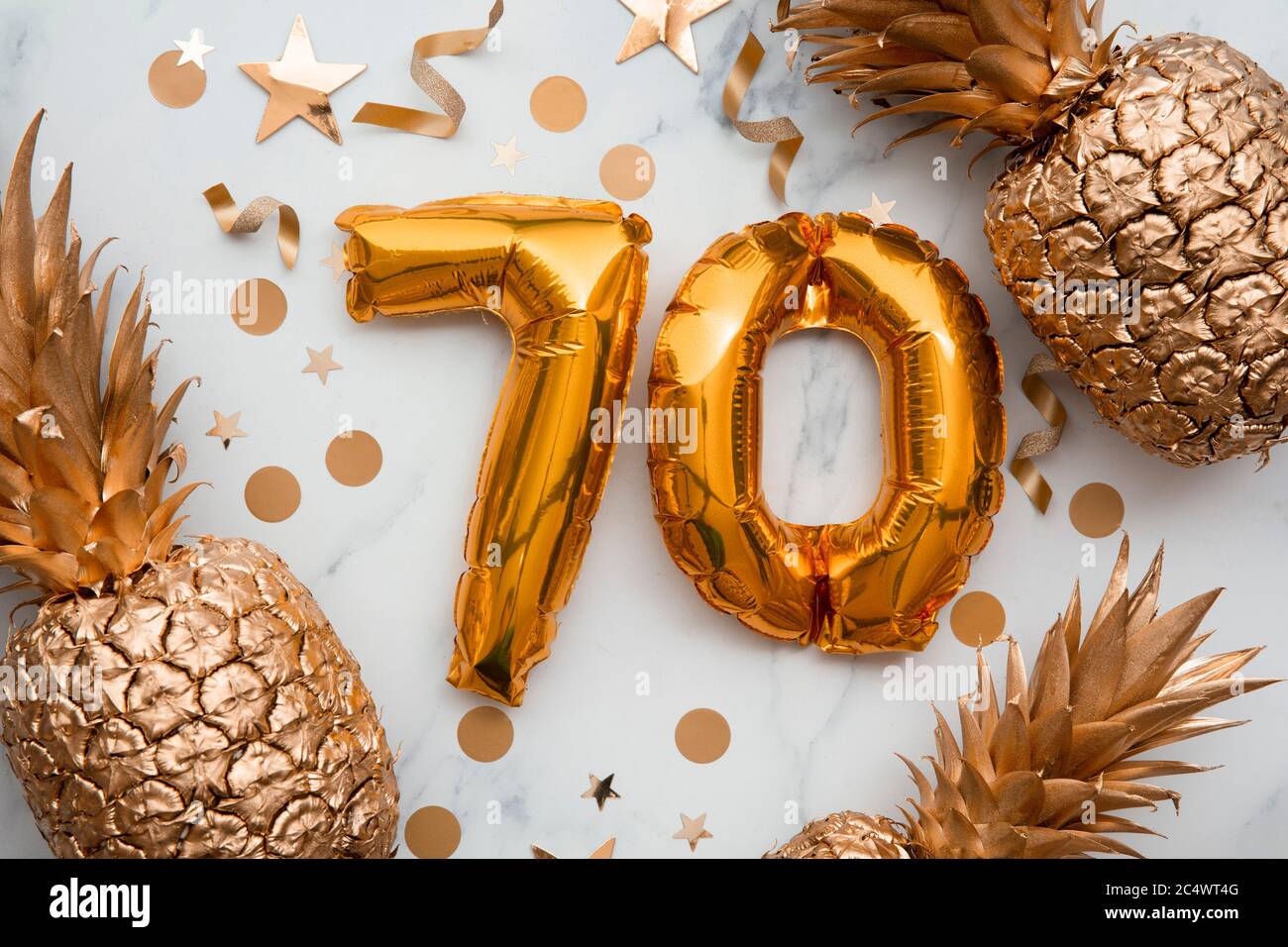 70th birthday celebration card with gold foil balloons and golden pineapples Stock Photo