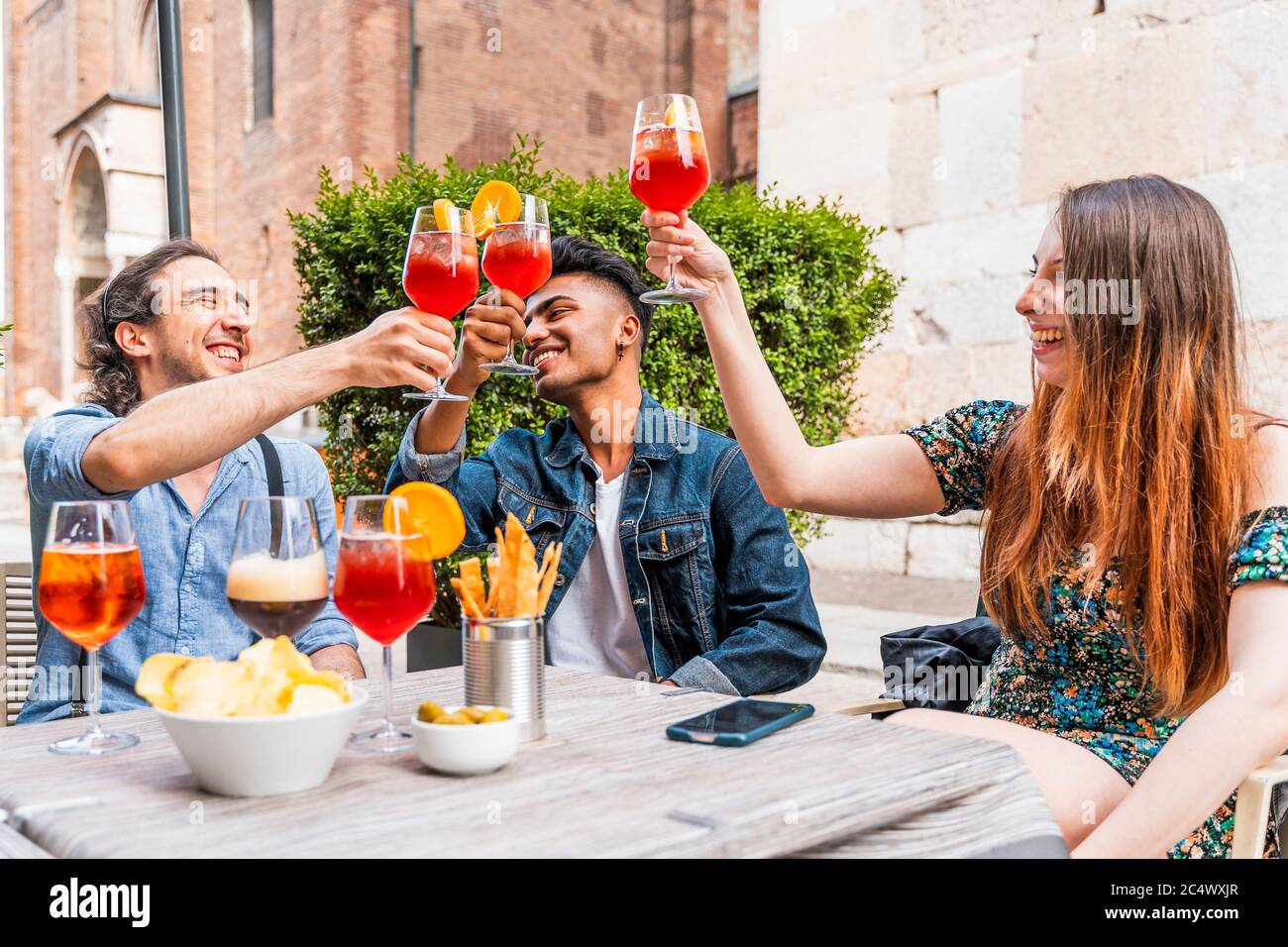 Friends drinking colored cocktail at outdoor bar New normal