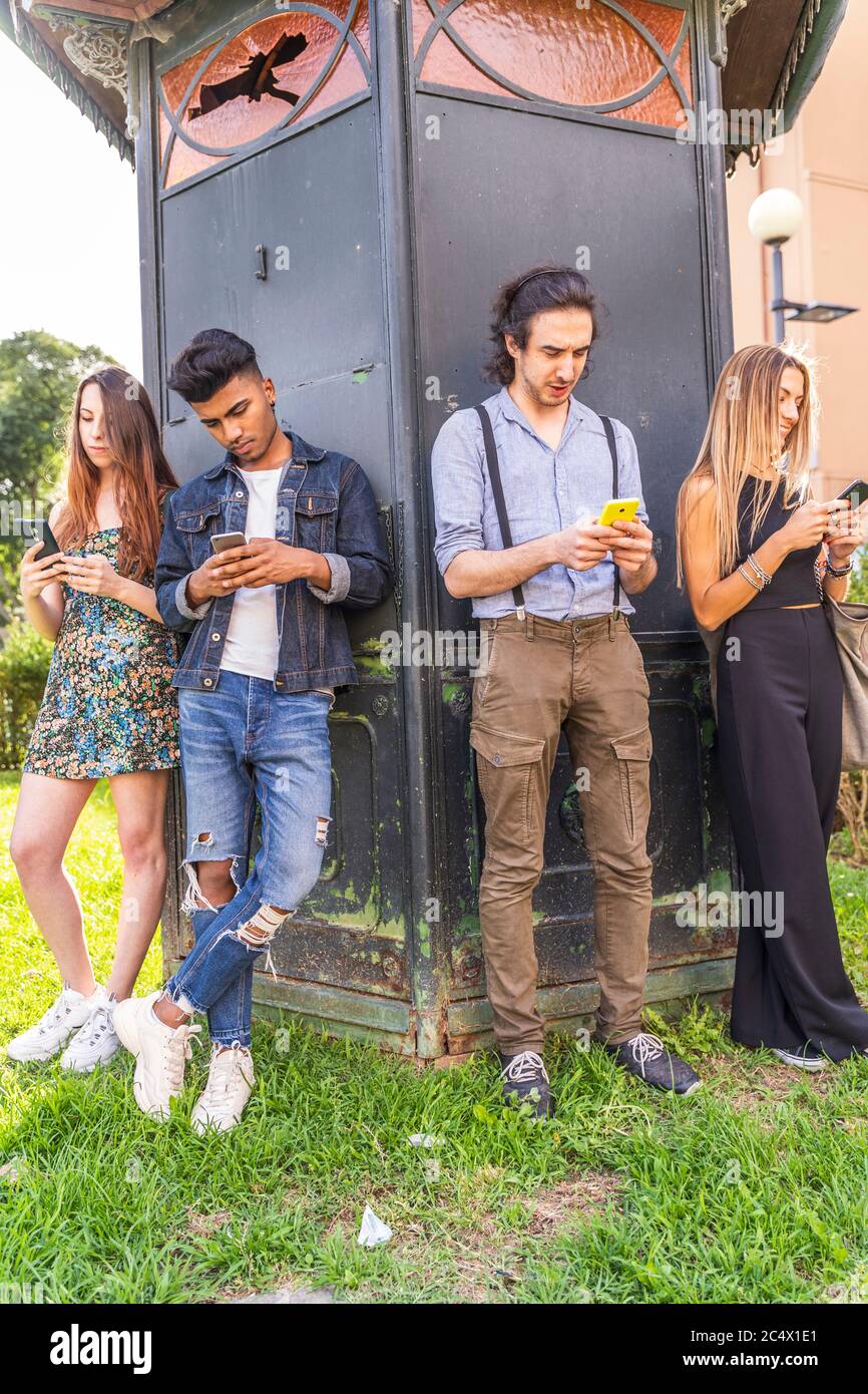 group of multiracial friends in front of a newsstand using smartphones to share content on social networks Stock Photo
