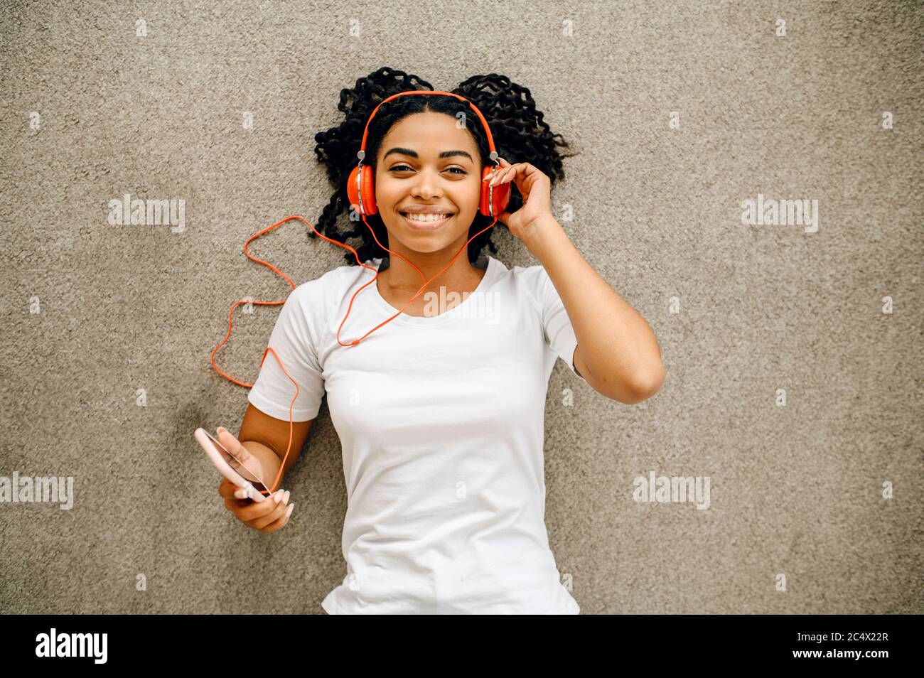 Woman lying on the floor and listen to music Stock Photo - Alamy