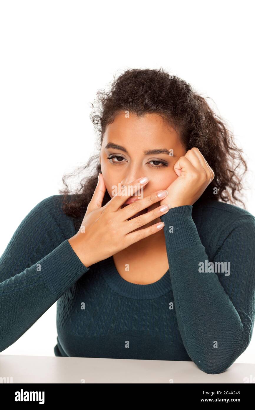 Young african tired and sleepy woman sitting at her desk on white background Stock Photo