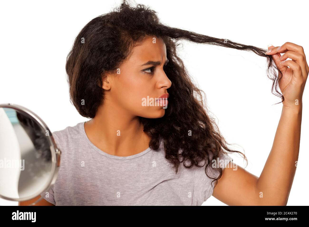 portrait of young dark-skinned woman with hair splitting problem on white background Stock Photo