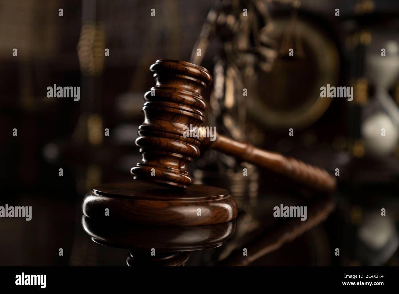 Law theme. Court library.  Gavel, scale and Themis statue on brown shining table. Collection of legal books in the bookshelf. Stock Photo