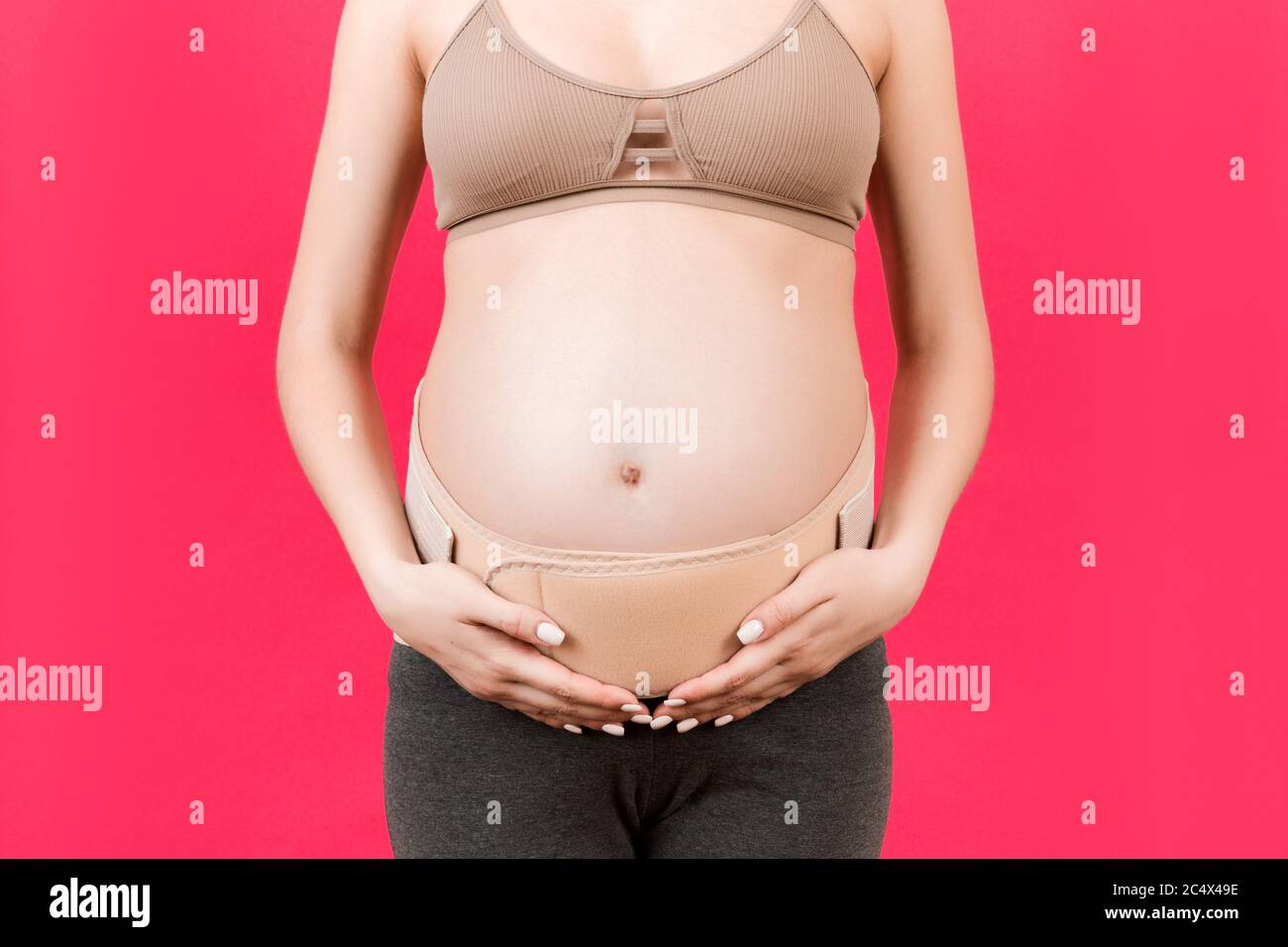 Closeup of pregnant woman wearing maternity girdle. Isolated over