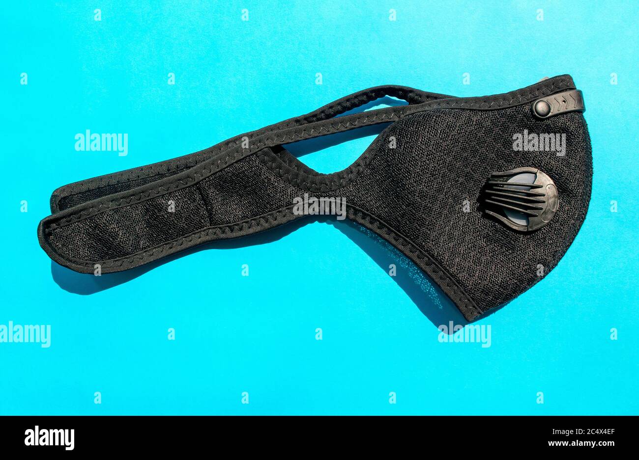 Black activated carbon dust mask with filters on blue background. Top