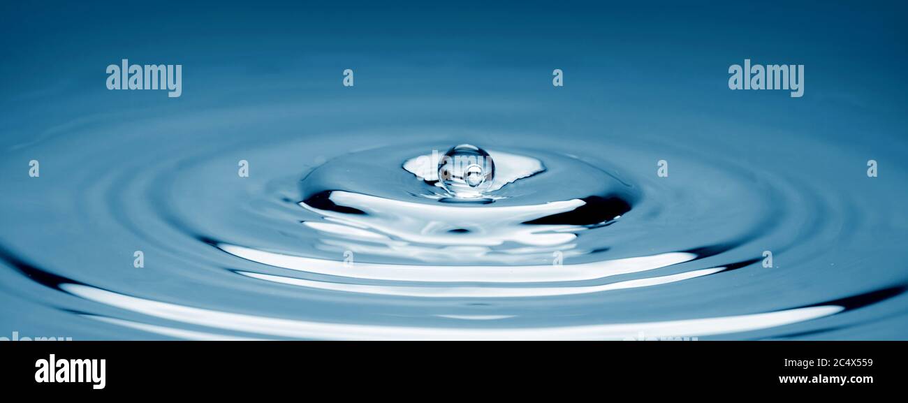 Water drop falling into water making a perfect concentric circles. Stock Photo
