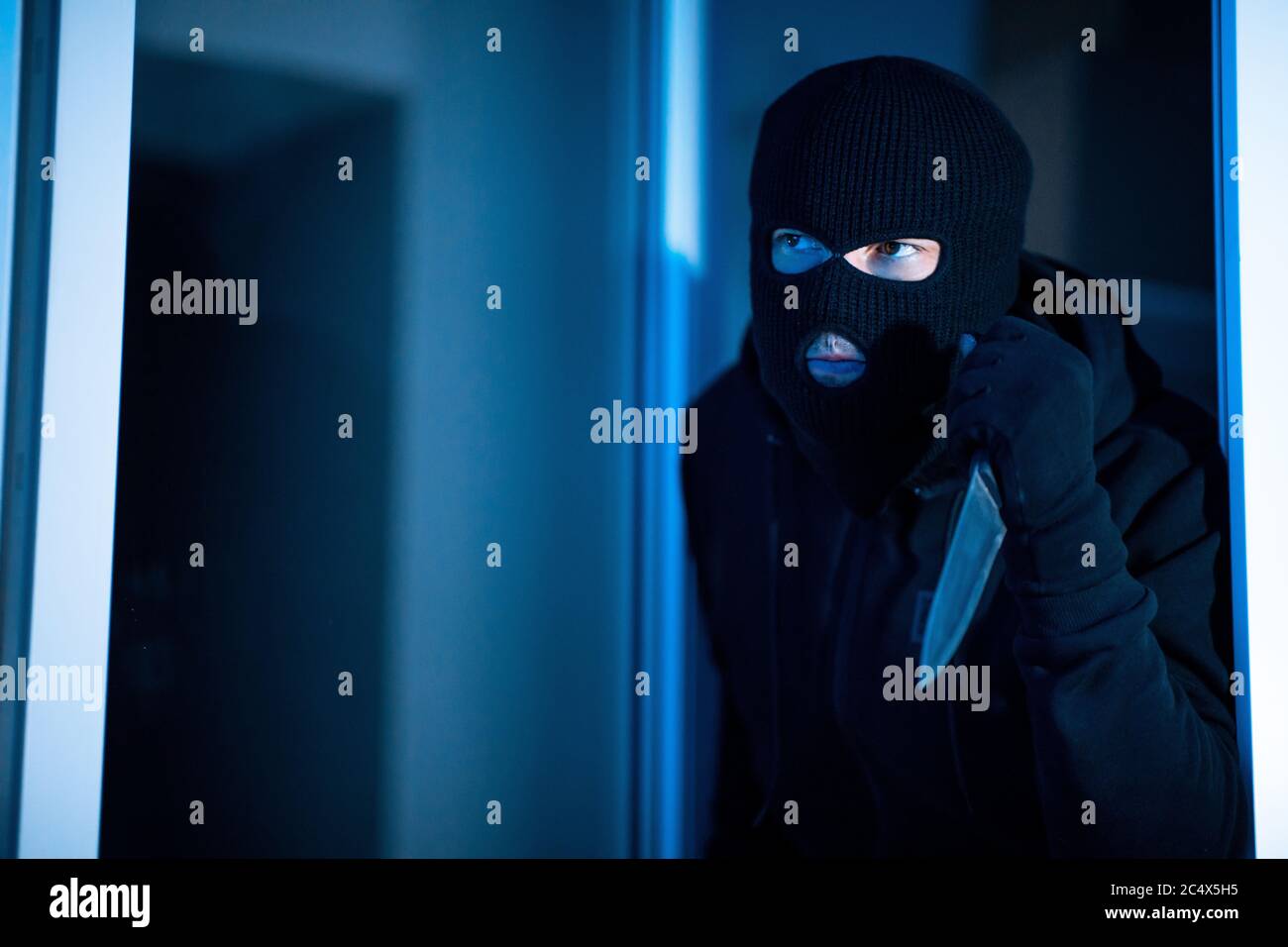 Criminal breaking in an apartment holding blade Stock Photo