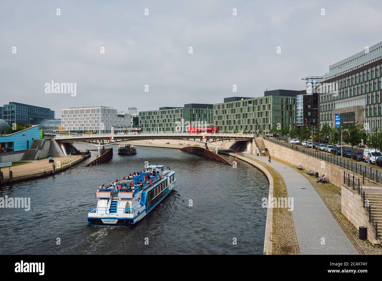 Tourist boats sailing along the Spree River, buildings with modern architecture, bridge over the river with passing sightseeing buses, Berlin, Germany. Stock Photo