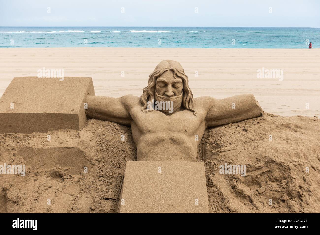 Las Palmas, Gran Canaria, Canary Islands, Spain. 29th June, 2020. Jesus  Christ wearing a face mask, the latest work of a local sand sculptor on a  tourist free city beach in Las