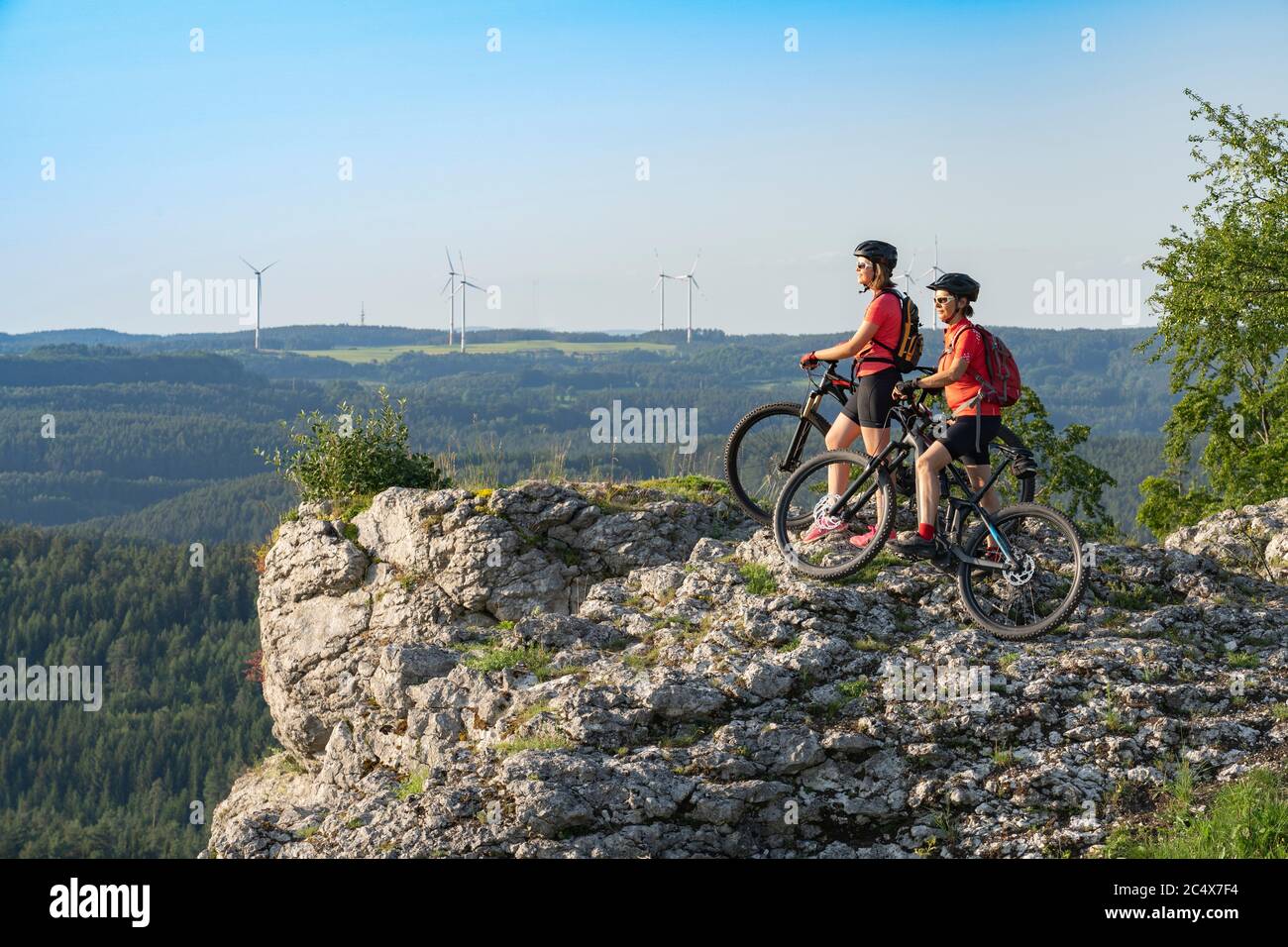 Grandmother with electric mountain bike and granddaughhter without electric help on a smooth meadow trail in the Franconian Switzerland area of Bavari Stock Photo