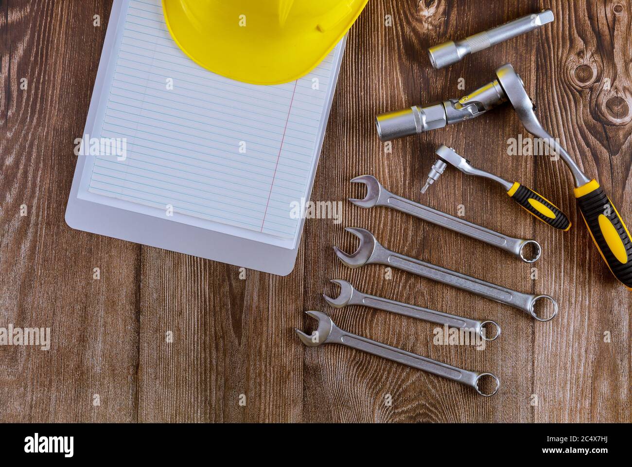 Setting spiral notepad of tools for auto mechanic, yellow safety helmet in spanner wrench automobile on wood background Stock Photo