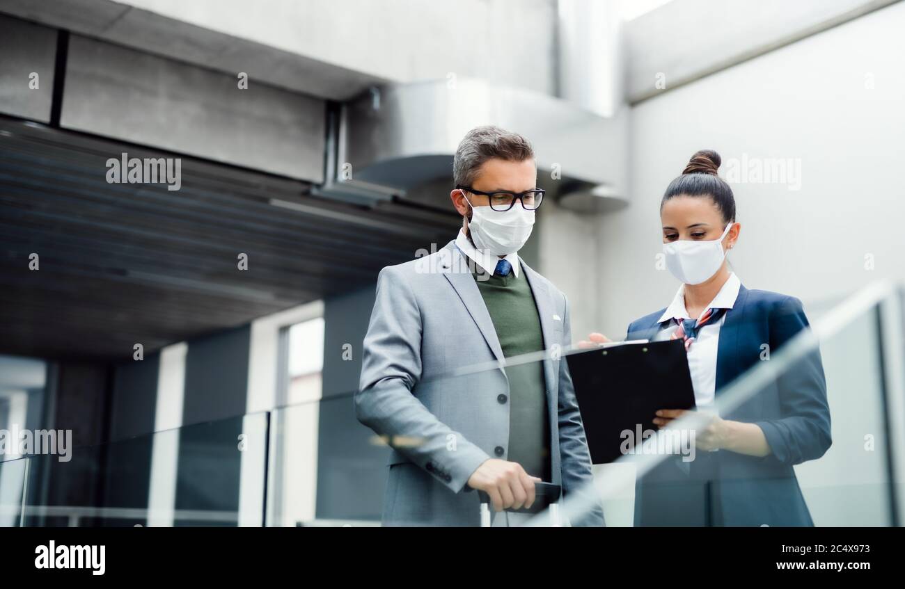 Flight attendant talking to businessman on airport, wearing face masks