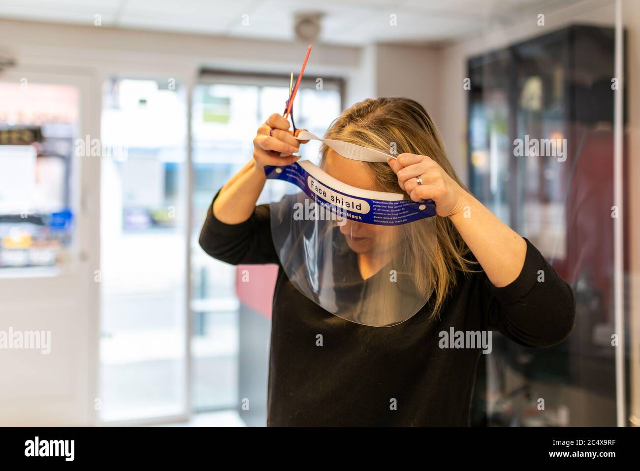 Hairdresser wearing face shield in a salon, after opening due to