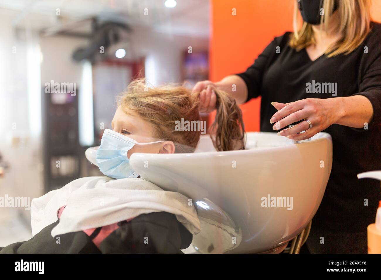 Girl having her hair washed in a hairdressing salon, wearing face masks after lockdown easing, UK Stock Photo