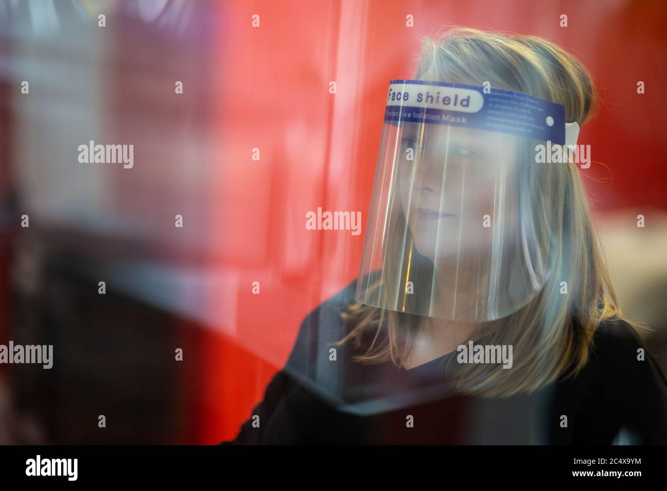 Hairdresser wearing face shield in a salon, after opening due to
