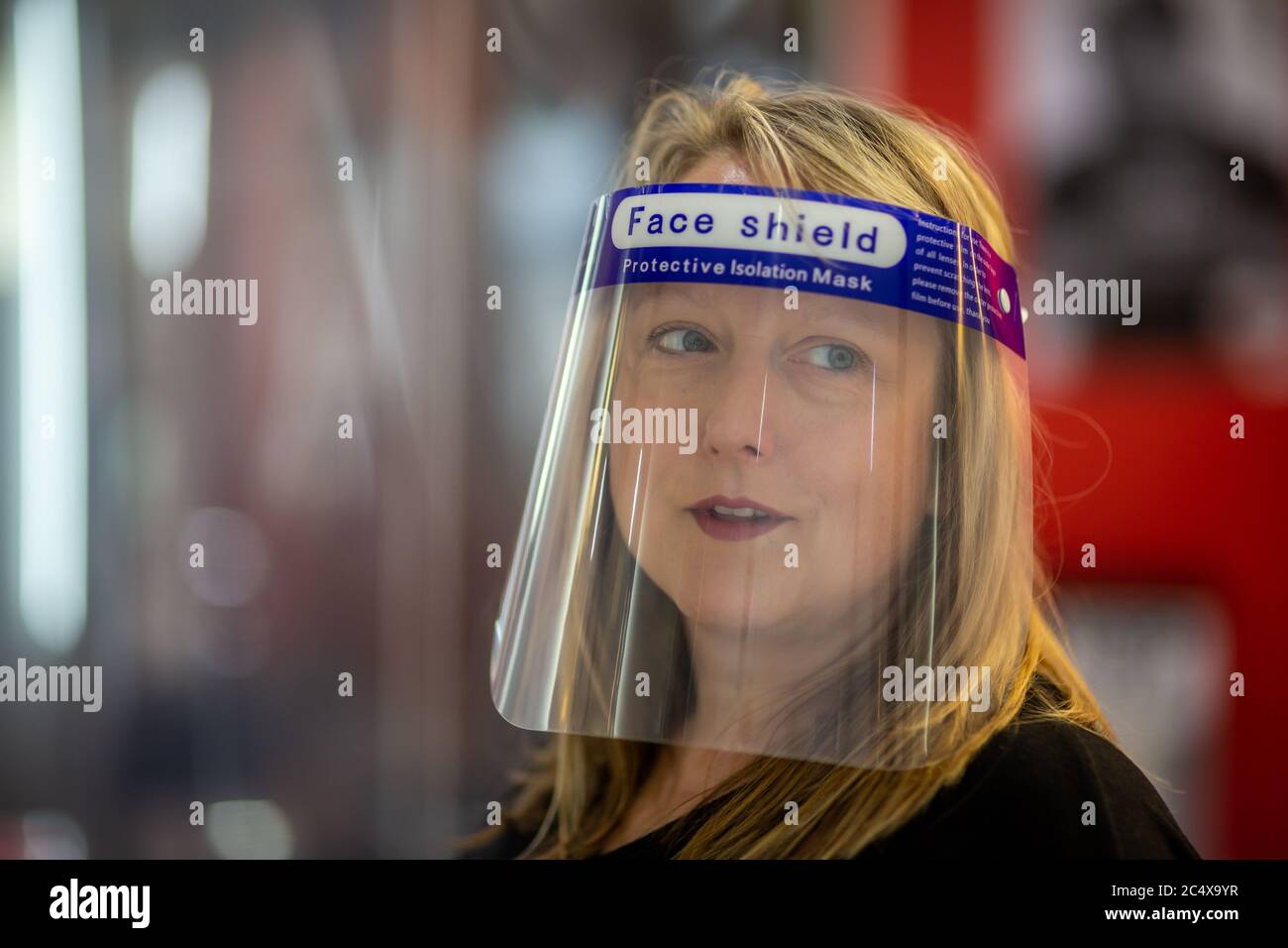 Hairdresser wearing face shield in a salon, after opening due to