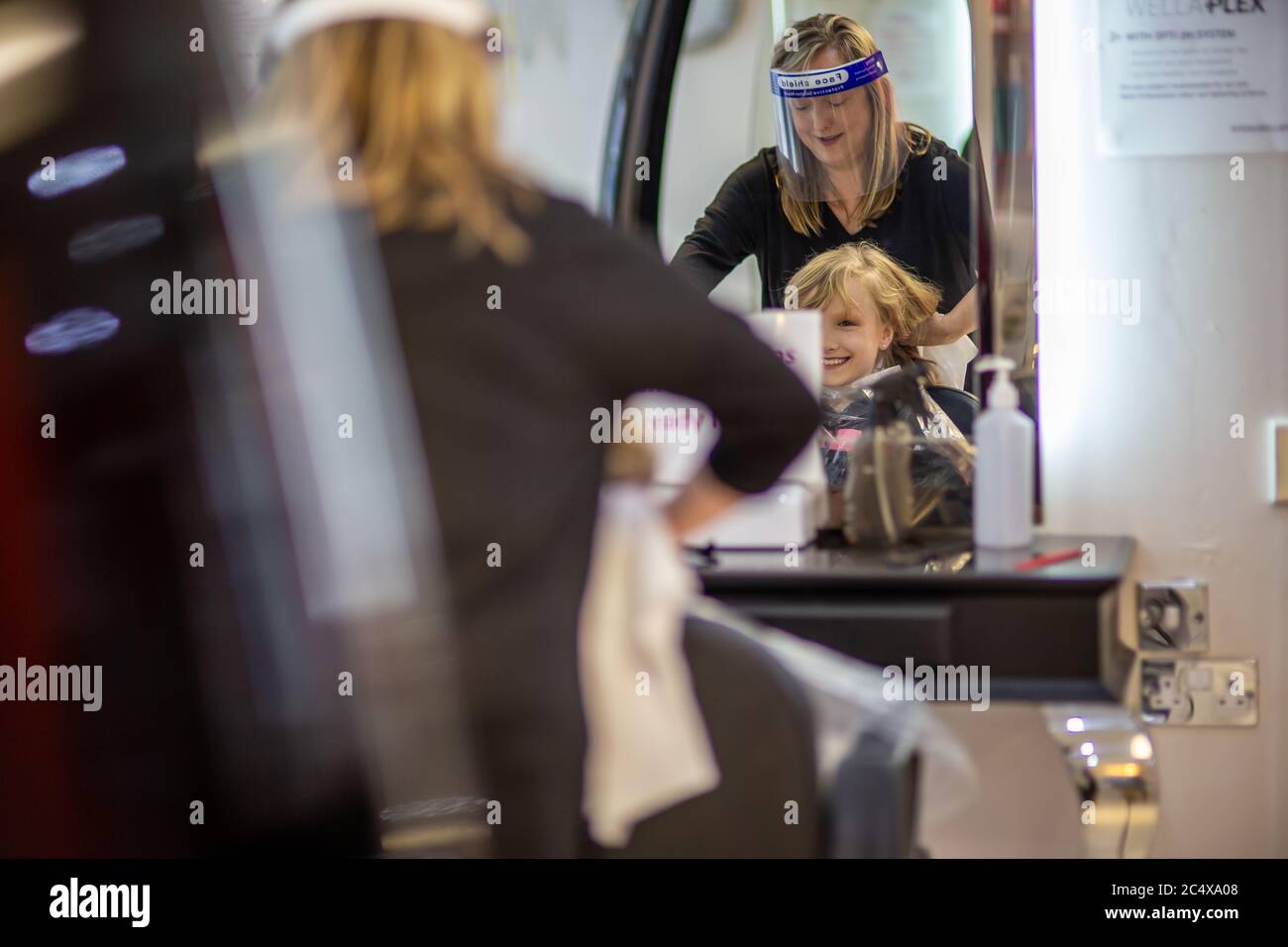 Hairdresser wearing face shield in a salon, after opening due to