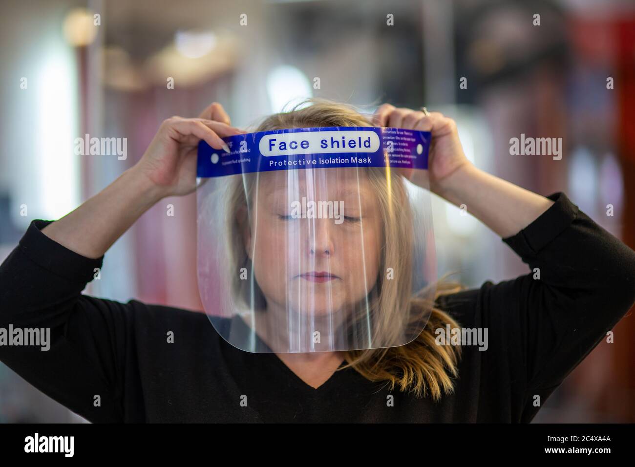 Hairdresser wearing face shield in a salon, after opening due to