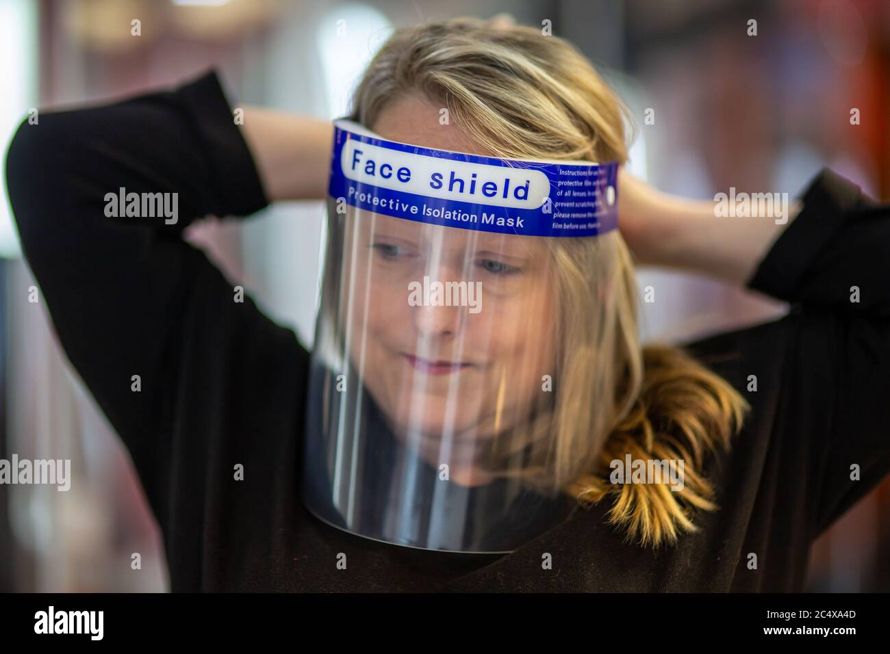 Hairdresser wearing face shield in a salon, after opening due to