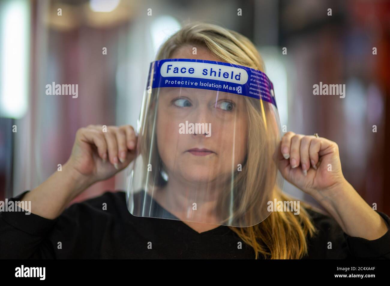 Hairdresser wearing face shield in a salon, after opening due to