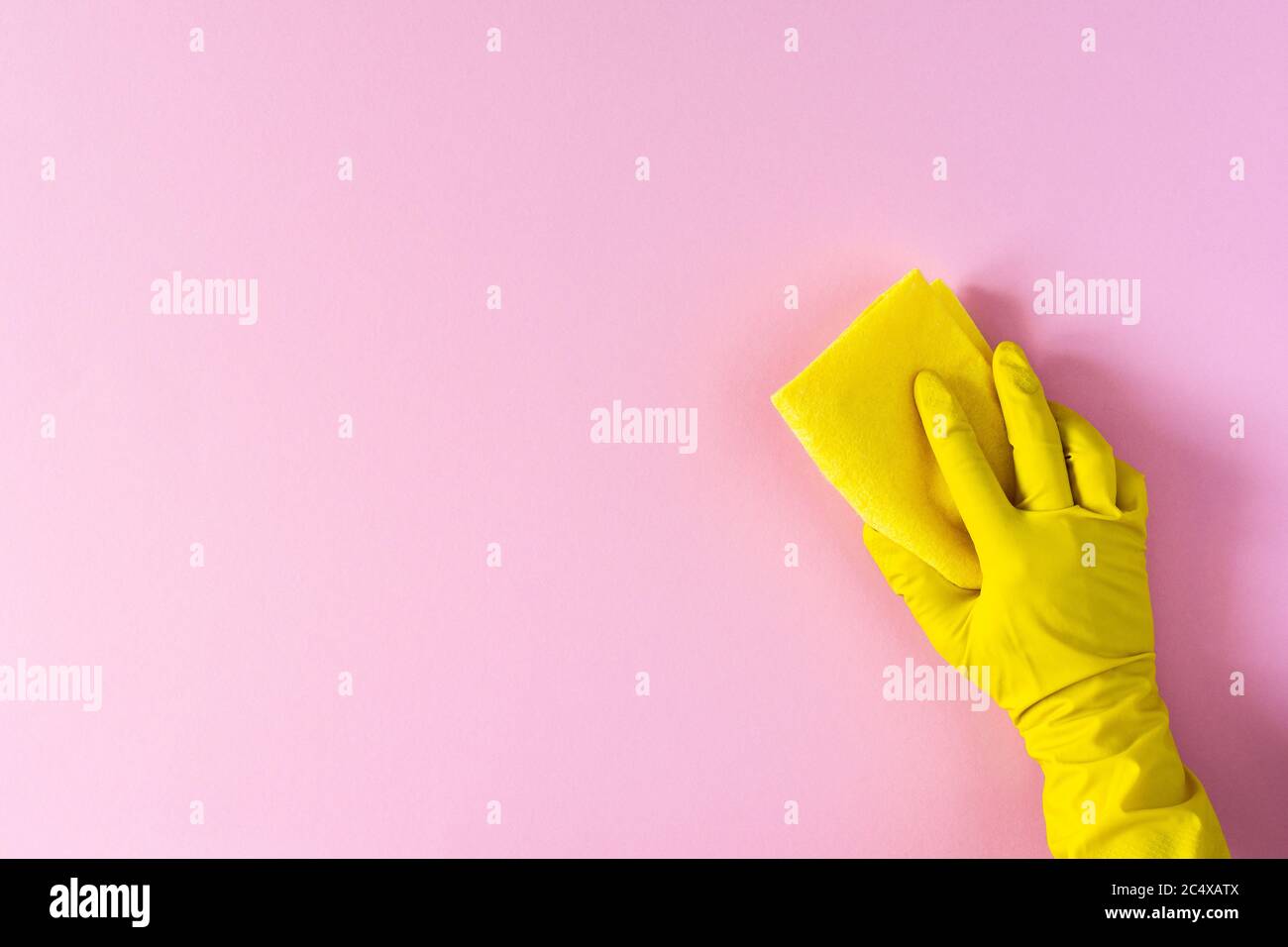 Hand in a yellow rubber glove with a cleaning sponge on a pink ...