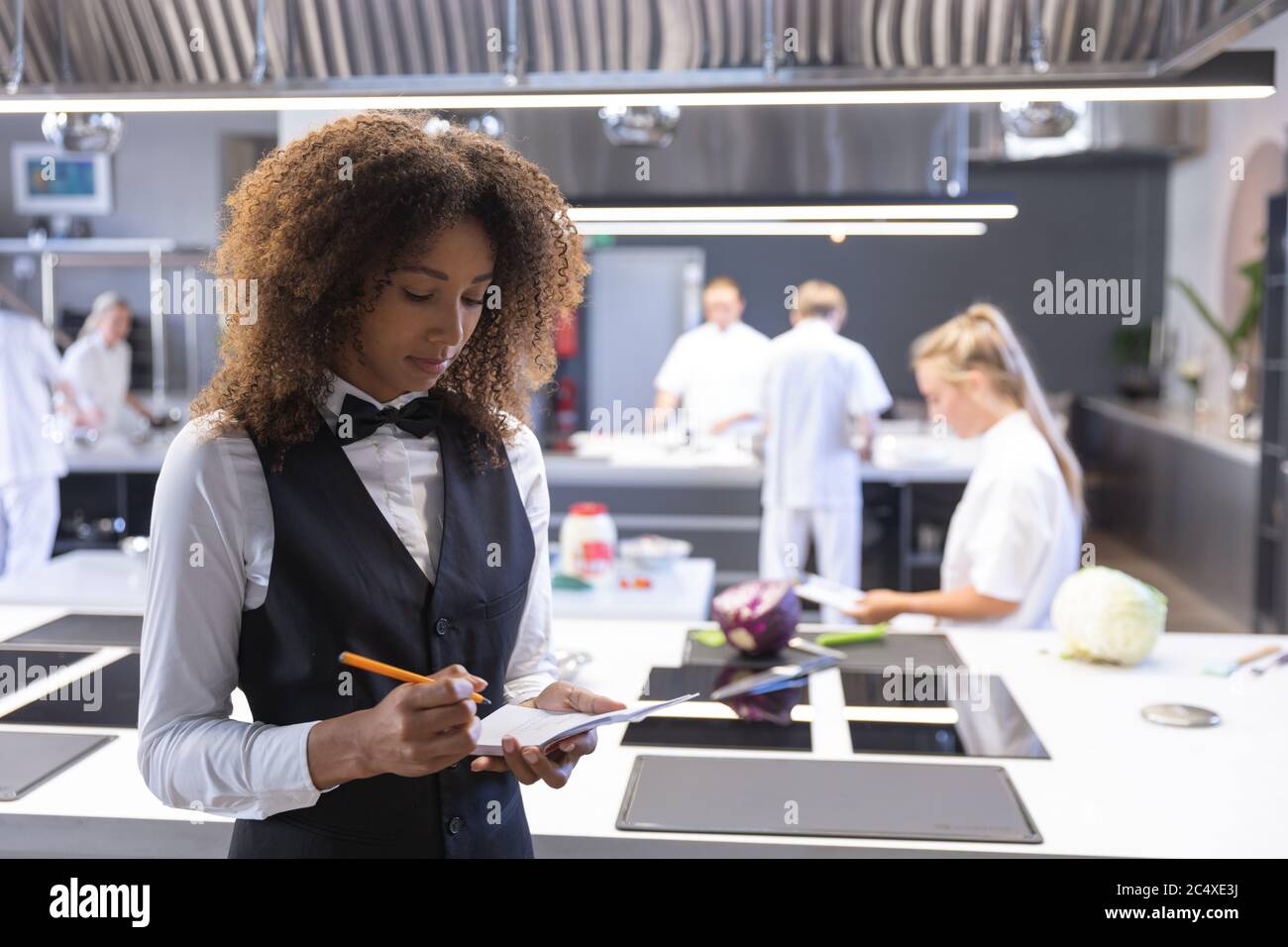 Female waitress writing in the notebook at restaurant kitchen Stock Photo