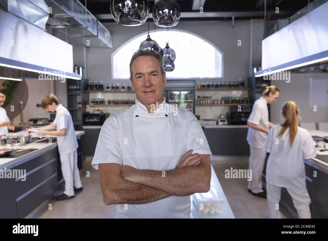 Portrait of senior male chef standing with his arms crossed at restaurant kitchen Stock Photo