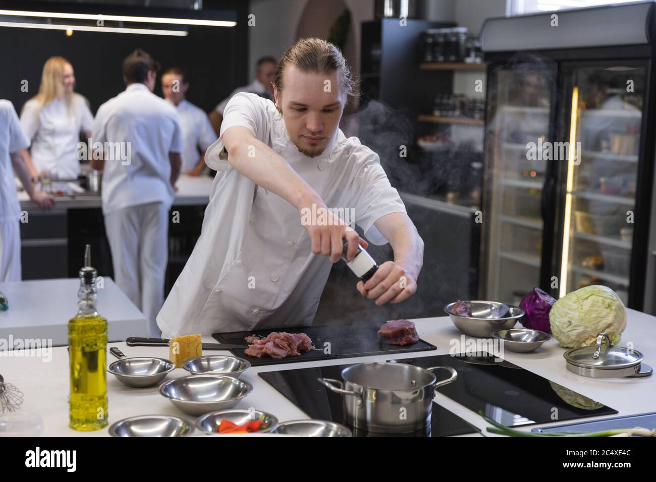 Young male chef adding salt in boiling water at restaurant kitchen Stock Photo