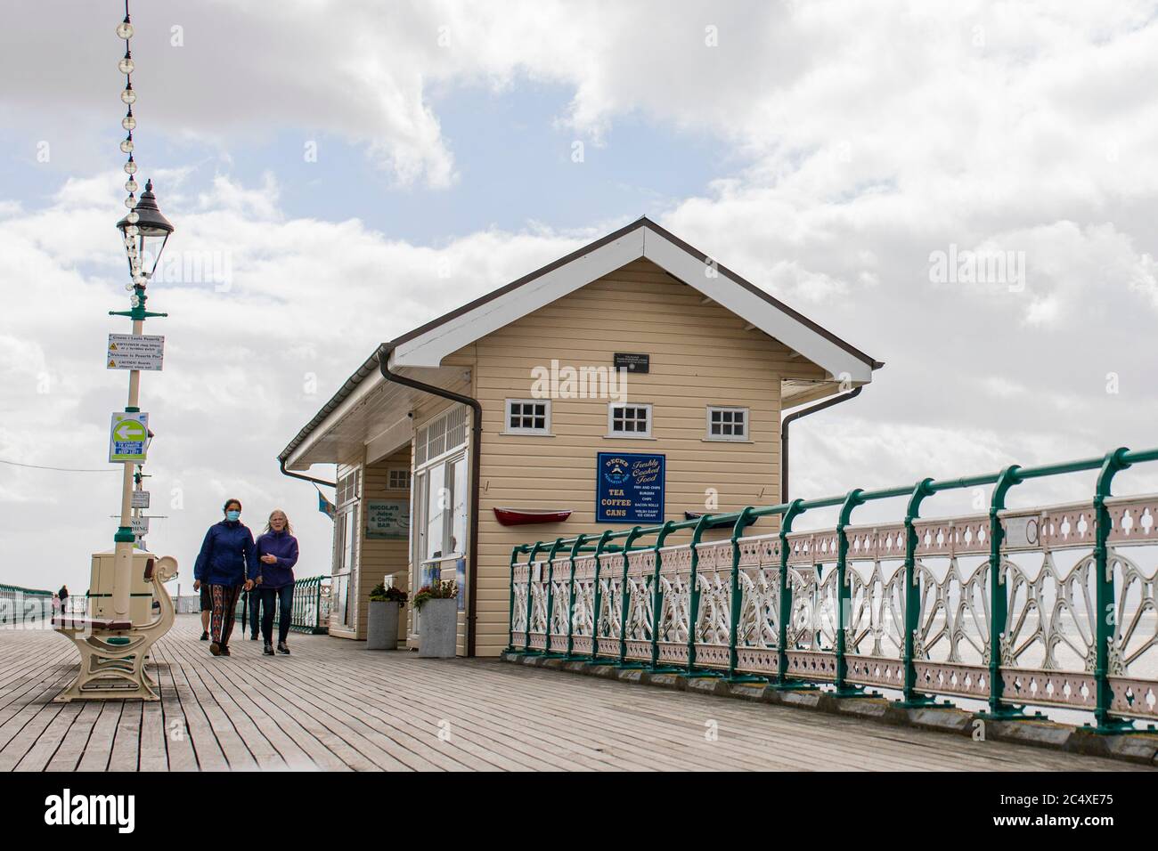 Penarth, Wales, UK. 29th June, 2020. Two women walk along Penarth Pier in the Vale of Glamorgan as the Welsh Government announces that two households will be able to form one 'extended household' from next Monday. Credit: Mark Hawkins/Alamy Live News Stock Photo