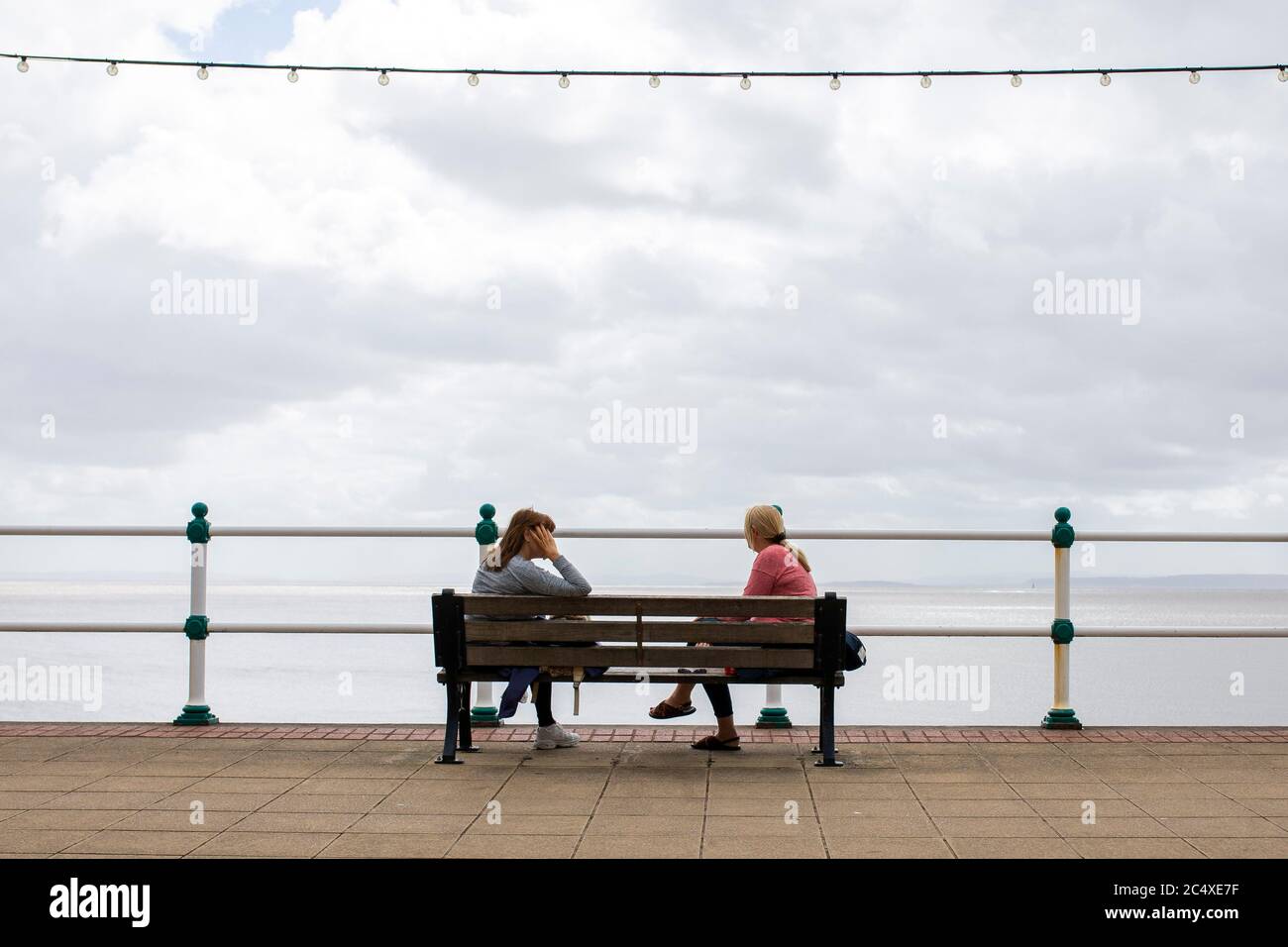 Penarth, Wales, UK. 29th June, 2020. Two women talk on a bench on Penarth promenade in the Vale of Glamorgan as the Welsh Government announces that two households will be able to form one 'extended household' from next Monday. Credit: Mark Hawkins/Alamy Live News Stock Photo