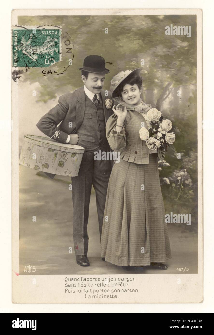 Original early 1900's French sentimental tinted greetings postcard - two young lovers, Man wearing a bowler hat, carries the woman's shopping, postally used green stamp on front of postcard France, circa 1911 Stock Photo